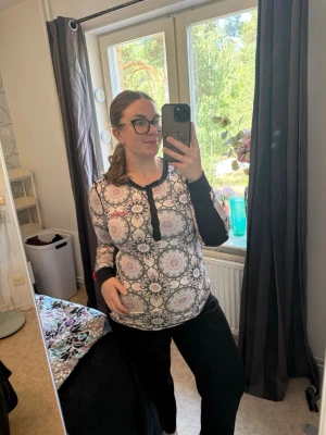 Mönstrad långärmad tröja - Säljer en långärmad loungewear-tröja med svart och vitt orientaliskt mönster, svarta detaljer längs ärmar och halsringning samt knappslå framtill. Tröjan har en avslappnad passform och är perfekt för mysiga dagar hemma. Från märket Odd Molly i storlek 4 som enligt deras storlekguide motsvarar en storlek L/XL. Mycket fint skick, jag hittar inga synliga anmärkningar eller defekter. 