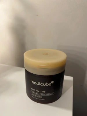 Medicube Deep Vita C Pad toner - Medicube Deep Vita C Pad är en toner i form av runda pads indränkta i vitamin C. Burken är mörkbrun med beige lock och innehåller pincett för enkel användning. Perfekt för dig som vill ha glow och fräsch känsla i huden.