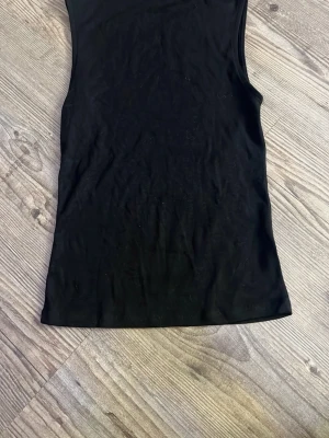 Svart ärmlös topp från Zara - Säljer en svart, enkel och stilren ärmlös topp från Zara. Toppen har en rak passform och är tillverkad i ett mjukt material som känns skönt mot huden. Perfekt att matcha med jeans eller kjol för en clean look.