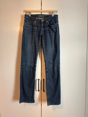 Mörkblå raka jeans från Acne Studios - Säljer ett par mörkblå jeans från Acne Studios med rak passform och klassisk femficksdesign. Jeansen har subtila slitningar och kontrastsömmar, tillverkade i denim av bomull. Perfekta för en avslappnad och stilren look.