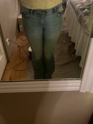 Ljusblå bootcut jeans med fjäril - Säljer ett par ljusblå bootcut jeans med snygg slitning och broderad fjäril på bakfickan. Jeansen har klassisk femficksdesign och hög midja. Perfekta för dig som gillar en retro vibe och vill ha något som sticker ut lite extra.