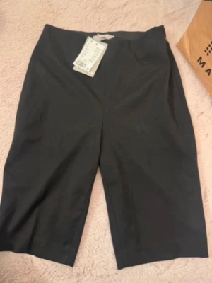 Svarta midwaist shorts från H&M - Stilrena svarta shorts från H&M med midwaist passform. Klassisk rak modell som passar perfekt till sommaren. Tillverkade i ett mjukt och bekvämt material som känns skönt mot huden. Enkla att matcha med olika toppar för en clean look.