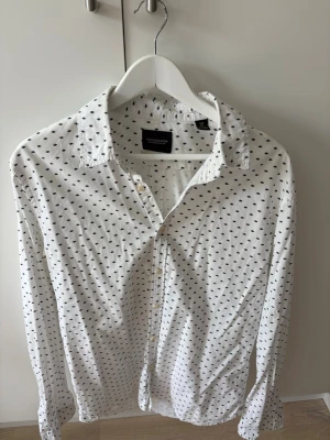 Vit skjorta med mönster från Scotch & Soda - Säljer en vit skjorta från Scotch & Soda med små mörkblå mönster över hela skjortan. Snygg skjorta med häftiga mönster! 