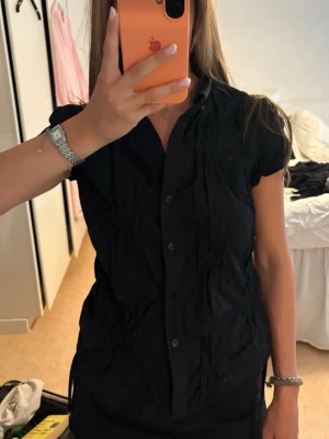 Svart kortärmad blus med knappar - Svart kortärmad blus med knappar från vila i storlek m, men skulle säga att den mer är som en s💓