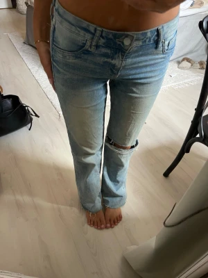 Ljusblå raka jeans med slitning - Säljer ett par ljusblå jeans med rak passform och en snygg slitning vid knät. Jeansen har klippts av nertill, de passar någon som är 160-165cm lång. 