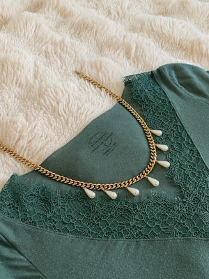 Guldfärgat halsband med pärldroppar - Snyggt halsband med  guldfärgad kedja och vita pärldroppar som hänger längs kedjan. Perfekt accessoar för att lyfta din outfit med en trendig och elegant touch.