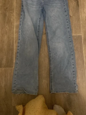 Ljusblå raka jeans - Säljer ett par ljusblå jeans med rak passform och klassisk femficksdesign. Jeansen har normal midja och är tillverkade i denim. Perfekta för en avslappnad och trendig look.