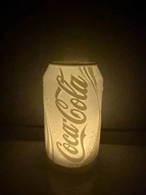 Vit Coca-Cola burkformad lampa - Unik lampa i form av en Coca-Cola burk, helt vit och tillverkad i plast. Lampan har detaljerat reliefmönster med Coca-Cola-loggan och kan användas som mysbelysning eller dekoration. Perfekt för dig som gillar coola  inredningsdetaljer.                                                     LED värme ljus hänger med
