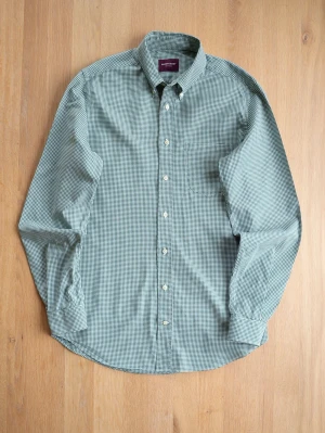 Grön rutig skjorta från Shirtonomy - Klassisk grön och vit rutig skjorta från Shirtonomy med lång ärm och knappar framtill. Skjortan har button-down krage och bröstficka. Tillverkad i mjuk bomull som känns skön mot huden. Perfekt för en avslappnad men ändå stilren look.