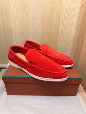 Loro Piana Summer Walk  - Snygga loafers i röd mocka med stilren design och vit gummisula. Skorna har en klassisk slip-on-modell utan snörning och en mjuk ovandel i mocka som ger en lyxig känsla. Perfekta för dig som vill sticka ut med färg och komfort.