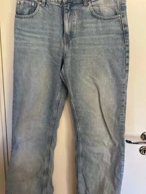 Ljusblå raka jeans - Säljer ett par ljusblå jeans med rak passform och klassisk femficksdesign. Jeansen har hög midja och är tillverkade i ett slitstarkt denimtyg. Perfekta för en avslappnad och trendig look.