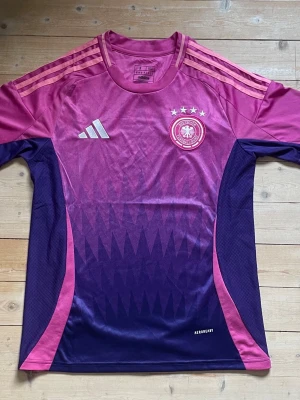 Tysklands matchtröja  - Säljer en Tysklands matchtröja från Adidas i snygg rosa och lila färgkombination. Tröjan har inga skador och är som ny. Den är i storlek S men passar även XS. Pris kan diskuteras 