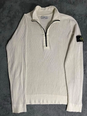 Stone Island – Beige Quarter Zip Knit Sweater (M) - Exceptionally rare Stone Island quarter‑zip knit sweater in a refined beige tone. Crafted from premium textured cotton with the iconic compass badge on the sleeve. Size M, length 68 cm, pit‑to‑pit 58 cm – relaxed and structured fit.  ✅ Condition: Excellent – no visible wear or damage 💯 Authenticity: 100 % genuine, can be verified via certilogo.com   💎 Retail price: Around €400 new 📦 Shipping: Fast dispatch after purchase  This piece represents Stone Island’s signature craftsmanship — durable