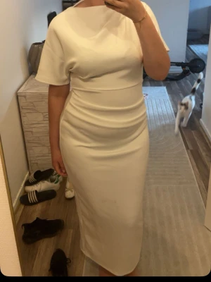 Elegant vit långklänning - Säljer en elegant vit långklänning med korta ärmar och rund halsringning. Klänningen har en figurnära passform och är tillverkad i ett mjukt, stretchigt material som ger en smickrande siluett. Perfekt för dig som vill ha en stilren och modern look.