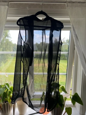 Svart kofta  - Säljer en svart kofta utan ärmar i ett tunt och luftigt material. Har en öppen front utan knäppning eller dragkedja. Perfekt för att lägga till en extra touch till din outfit.