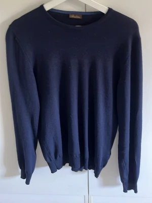 Stenströms tröja - En stilren mörkblå tröja med rund halsringning och långa ärmar. Tröjan har ribbade muddar vid ärmslut och nederkant, vilket ger en klassisk och clean look. Perfekt att matcha med jeans eller chinos för en avslappnad stil.