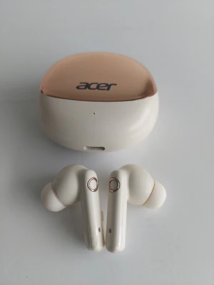 Acer trådlösa in-ear hörlurar - Snygga trådlösa in-ear hörlurar från Acer i vit och champagnefärgad design. Hörlurarna har silikontoppar för bekväm passform och kommer med ett matchande laddningsetui. Perfekta för musik, poddar och samtal på språng.