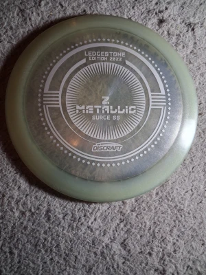 Lägg bud - Säljer en Discraft Z Metallic Surge SS Ledgestone Edition 2022 disc. Skivan är rund med en ljus genomskinlig kant och ett metalliskt mönster i mitten. Perfekt för discgolf och samlare av specialutgåvor. Helt ny fin disc!