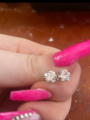 Silvriga örhängen med klara stenar 2par  - Säljer ett par stilrena silvriga örhängen med klara, gnistrande stenar i rund slipning. Perfekta som diskreta men ändå glittriga studs till vardagslooken. Stift och bakstycke i metall.