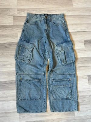 Baggy cargojeans - Baggy cargojeans i ljusblå denim med flera stora fickor på sidorna och framtill. Vida ben och avslappnad passform, perfekt för en streetwear-look. Klassisk femficksmodell med extra cargofickor och hällor för skärp.