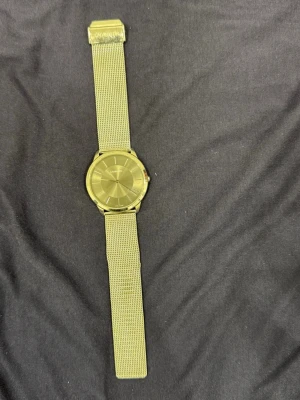 Silverfärgad klocka Calvin Klein - Stilren klocka från Calvin Klein i silver med mesh-armband och minimalistisk urtavla. Klockan har en rund form och metallarmband som ger en modern och clean look. Perfekt accessoar för dig som gillar enkel och tidlös design.