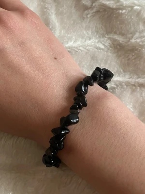 Svart pärlarmband  - Armband med svarta, oregelbundna pärlor i stenliknande form. Elastiskt band som gör det enkelt att ta på och av. 😊