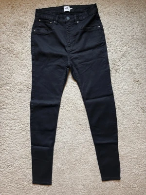 NYA Svarta  jeans - Helt nya och oanvända svarta jeans. Säljer ett par svarta jeans med tight passform och klassisk femficksdesign. Jeansen har bälteshällor och knappstängning framtill. Perfekta för dig som gillar en enkel och stilren look. Svarta jeans är ett måste i basgarderoben, passar till allt. Gör ett fynd idag!