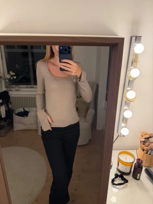 Beige långärmad topp med rund hals - Snygg beige långärmad topp med rundad halsringning och figurnära passform. Perfekt basplagg att styla till olika outfits. Tillverkad i mjukt material som känns skönt mot huden.
