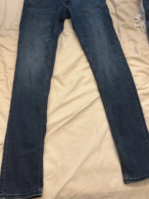 Mörkblå slim jeans - Säljer ett par mörkblå slim fit jeans med klassisk femficksdesign. Jeansen har en smal passform och är tillverkade i mjuk bomull med lite stretch för extra komfort. Perfekta till vardags och enkla att matcha med olika stilar.