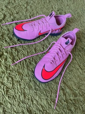 Nike Air Zoom Mercurial Vapor inomhusskor stl 38 - Superfina rosa/lila Nike Air Zoom Mercurial Vapor inomhusfotbollsskor i storlek 38 (innermått 24 cm). Snygg modell med ljusröda/crimson detaljer och "Air Zoom"-dämpning. Flat gummisula som inte lämnar märken på golvet. Använda ett fåtal gånger och i mycket fint skick.