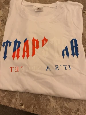Vit Trapstar t-shirt med tryck - Säljer en snygg tröja med färgerna av röd vit och blå bra om du vill sticka ut lite 