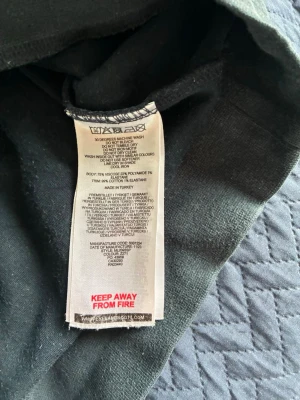 Mörkblå sweatshirt från Lyle & Scott - En stilren mörkgrön sweatshirt från Lyle & Scott med klassisk rund halsringning och den ikoniska gula örnloggan broderad på bröstet. Tillverkad i en mjuk blandning av viskos, polyester, bomull och elastan för skön komfort. Perfekt till alla kläder och väder