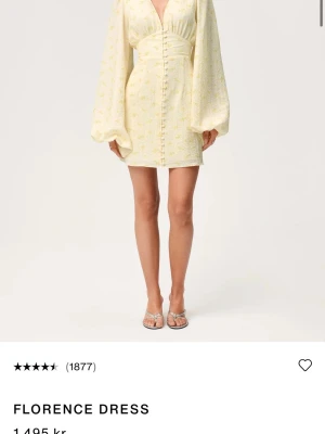 Gulblommig kort klänning med puffärm - Supersöt kort klänning i ljusgul nyans med små gula blommor. Djup v-ringning, puffiga långärmar och knappar framtill. Materialet är strukturerat och känns som bomull eller polyester. Perfekt för sommarens alla tillfällen!Liten tråd som sticker ut men inget man lägger märke till💕