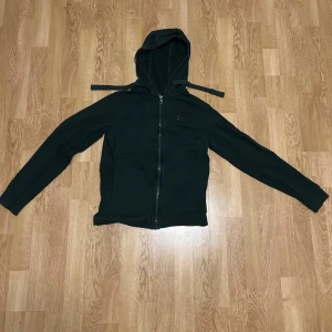 Svart hoodie från EA7 Emporio Armani - Snygg svart hoodie från EA7 Emporio Armani med dragkedja framtill och huva med snören. Tillverkad i mjukt material och har diskret logga på bröstet. Perfekt för en avslappnad och trendig look.