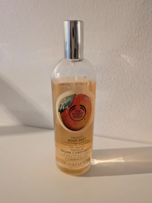 Mango Body Mist från The Body Shop - Fräsch body mist med mangodoft från The Body Shop. Kommer i en genomskinlig glasflaska med silverfärgad spraykork och en färgglad etikett med mangomotiv. Flaskan är 100 ml, se bilder för att se hur mycket som är kvar ☺️