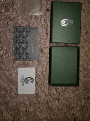  Svart-grå kortfodral - Snyggt grått kortfodral  med klassiskt mönster och präglad logga. Tillverkad i läder och canvas, perfekt för kort och ID. Kommer med originalask och Gort. Stilren och exklusiv accessoar för dig som gillar lyxiga detaljer.