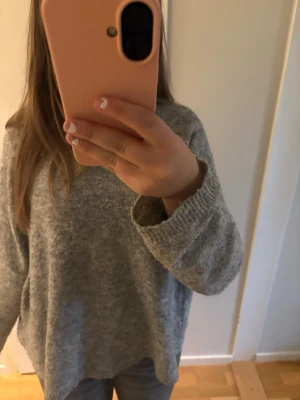 Grå stickad tröja från BikBok - Mysig grå stickad tröja från BikBok i storlek S. Tröjan har en avslappnad passform, rund halsringning och ribbade muddar vid ärmslut och nederkant. Perfekt för lager på lager och enkel att matcha med jeans eller kjol.