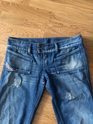 Lågmidjade bootcut diesel jeans med slitningar - Säljer ett par lågmidjade bootcut jeans från diesel med markerade slitningar och tvättade detaljer. Ca 42cm rakt över midjan 💕