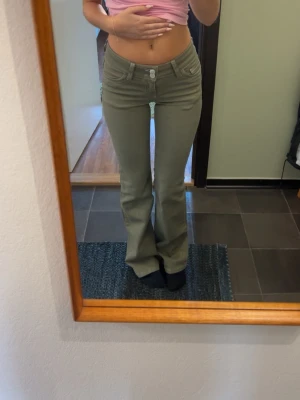 Jeans  - Snygga olivgröna jeans med bootcut passform och låg midja. Jeansen har klassiska fickor och coola vita sömdetaljer på bakfickorna. Perfekta för dig som vill ha en trendig och avslappnad look. Helt nya aldrig använda 