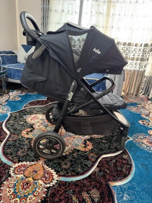 Svart barnvagn från Joie - Säljer en svart barnvagn från Joie med justerbart ryggstöd, stor sufflett och fempunktssele. Vagnen har svängbara framhjul, praktisk varukorg undertill och avtagbar bygel. Passar perfekt för promenader i stan eller parken.