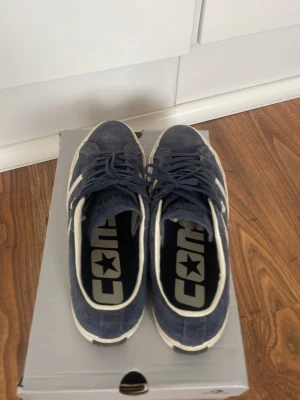 Blå Converse One Star sneakers - Snygga blå Converse One Star sneakers i mocka med vita detaljer och snörning. Klassisk låg modell med vit sula och stjärndetalj på sidan. Perfekta för dig som vill ha en stilren och tidlös sneaker till vardagslooken. Knappt använda alls 