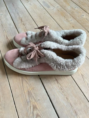Rosa sneakers  - Unika sneakers i ljusrosa mocka med fluffiga pälsdetaljer runt hela skon och på plösen. Skorna har matchande rosa snören och vit sula. 