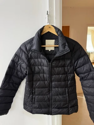 Svart dunjacka från Part Two - Snygg svart dunjacka från Part Two med quiltat mönster och hög krage. Jackan har dragkedja framtill och två sidofickor. Perfekt för kalla vinterdagar och ger en stilren look. Materialet är lätt och värmande.