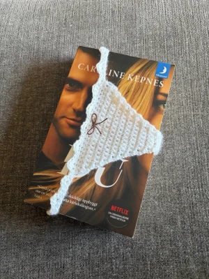 Vitt virkat bokmärke  - Ett bokmärke i form av en trosa med spetskant och en liten rosett framtill 