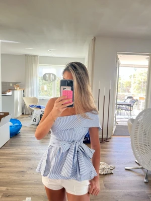 Randig offshoulder topp med knyt - supersnygg blåvit randig offshoulder topp med knyt i midjan och volang nertill. kan stylas och knytas på olika sätt. storlek S-M med dragkedja på sidan. vet inte vad för märke🥰