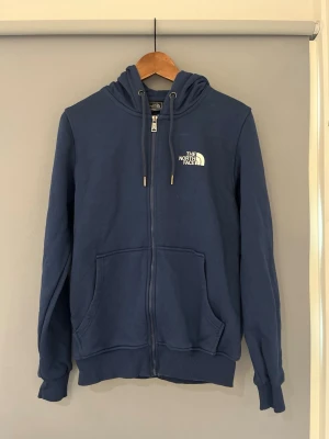 Blå hoodie från The North Face - Blå hoodie från north face som inte kommer till användning längre. Storlek S inga defekter, använd en del. Riktigt varm hör av er vid minsta funderingar!
