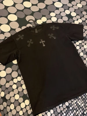 Chrome Hearts t - shirt - Riktigt kors i metall på framsidan vilket inte stör alls men är extremt snyggt, dessutom är det en detalj på ryggen gjort i metall. Sjukt fet tröja i storlek M, skulle inte missa denna.