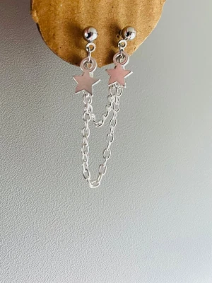 1 st Silvrigt örhänge med stjärnor och kedja - Snyggt silvrigt  örhänge med små stjärnberlocker och dubbla kedjor som hänger mellan örsnibbarna. Örhänget har en minimalistisk och trendig design, perfekta för dig som gillar detaljer och vill sticka ut lite extra.