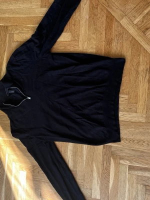Svart stickad halv zipp H&M - Svart stickad tröja från H&M med halv dragkedja vid halsen. Tröjan har lång ärm och ribbstickade muddar. Enkel och stilren design som passar till många olika outfits.