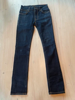 Mörkblå raka jeans - Säljer ett par mörkblå jeans med raka ben och klassiska kontrastsömmar. Storlek W27 L32